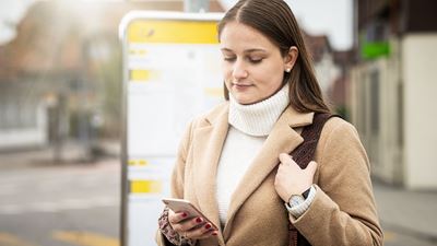 A woman checks her mobile phone at the PostBus stop.