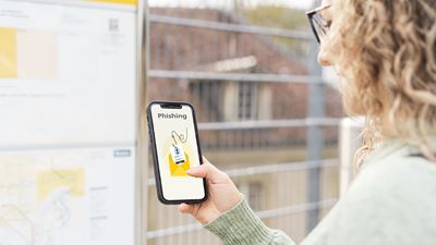 Eine Person informiert sich mit Smartphone zum Thema Phishing