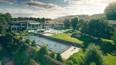 Grosses Schwimmbeck in Parkanlage mit Häusern im Hintergrund.
