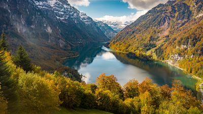 Der Klöntalersee umzingeld von schneebedeckten Bergen in herbstlicher Stimmung.