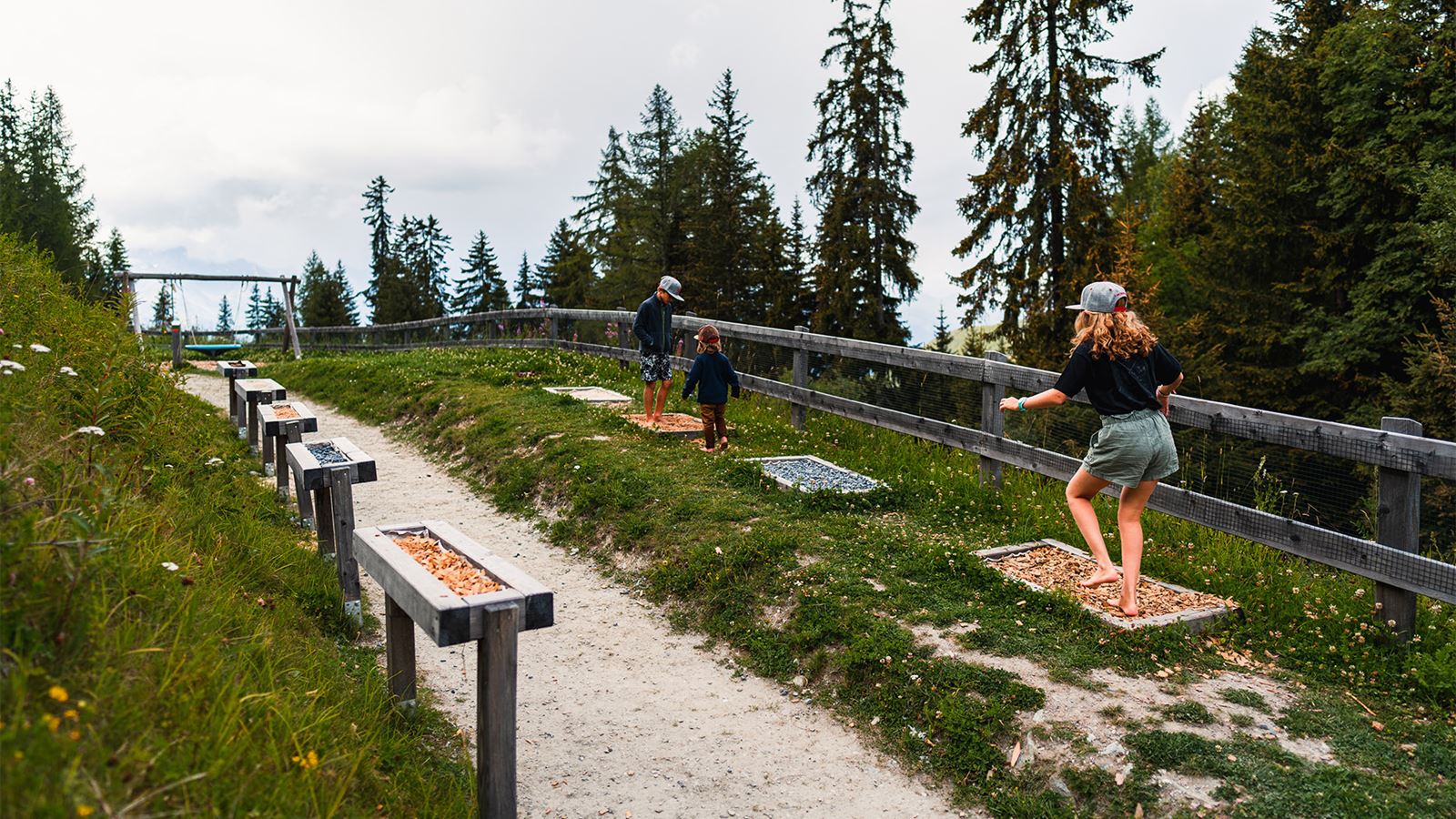 “Sentier des Sens” trail, La Tzoumaz: family having fun walking barefoot on a variety of different surfaces