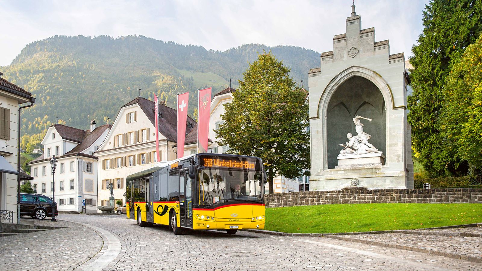 Le car postal, appelé le car de Winkelried, passe devant le monument de Winkelried à Stans.