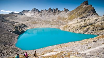 Wanderer laufen entlang am himmelblauen See vorbei