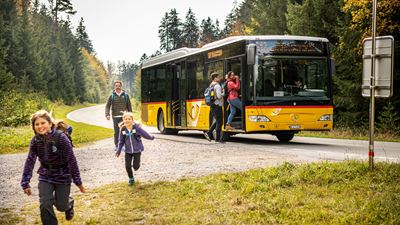 Familie auf einem Ausflug in die Natur steigt aus einem PostAuto, Teil des RailAway Angebots, um ein Freizeit-Erlebnis mit Rabatt zu geniessen.