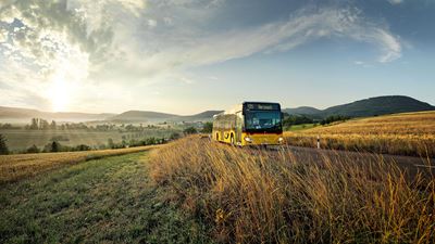 A Postbus in hilly landscape, with sunlight behind