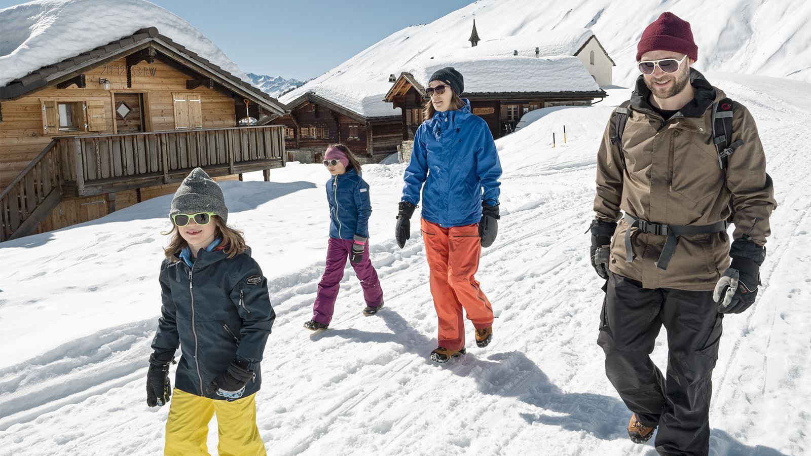 Una famiglia cammina in montagna durante una bella giornata invernale.