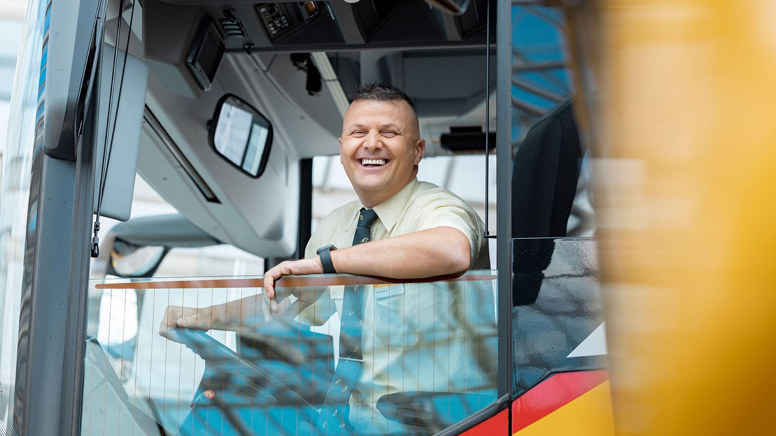A Postbus driver looking out of the driver’s window with a laugh