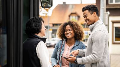 A Postbus driver talking to two passengers