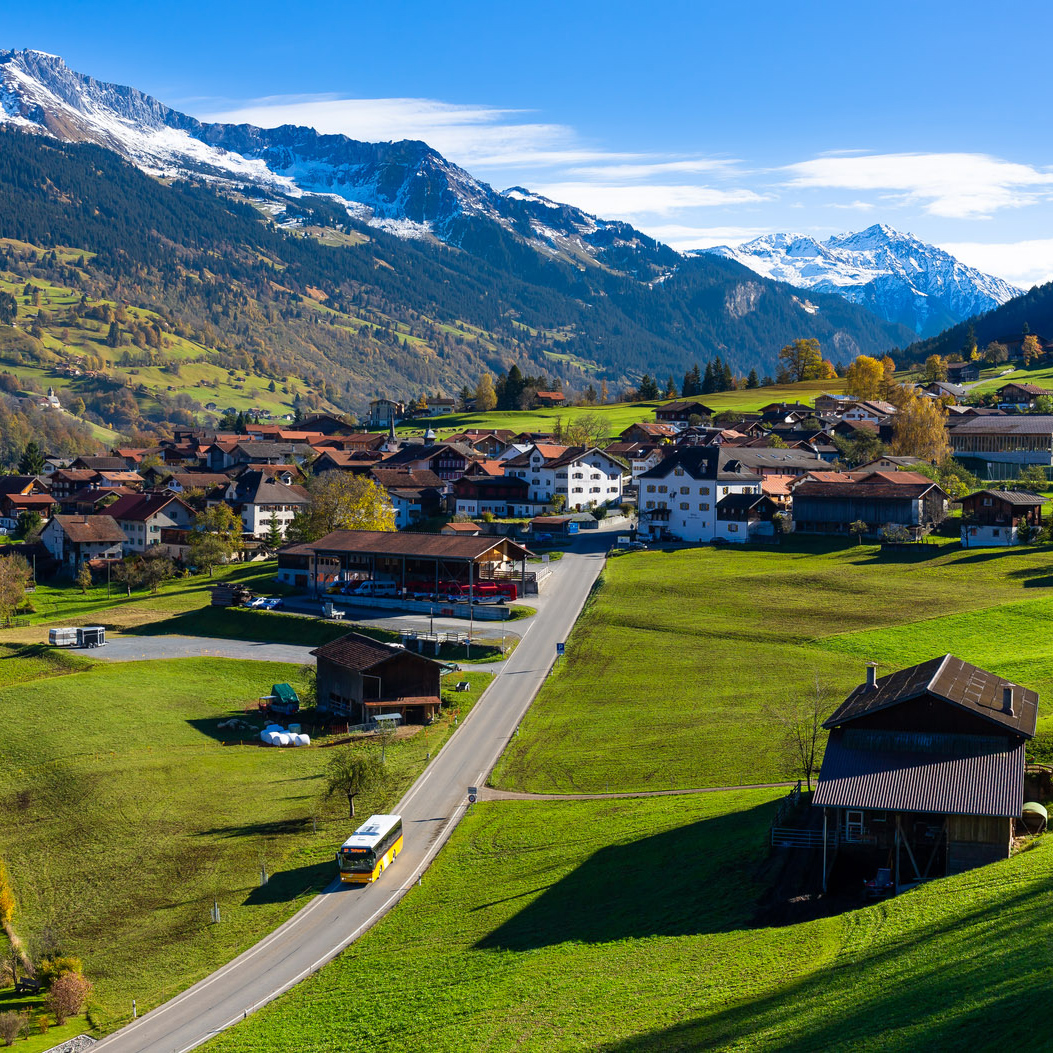 Regional passes – Postbus with the graubündenPASS driving through a Graubünden village against an Alpine backdrop