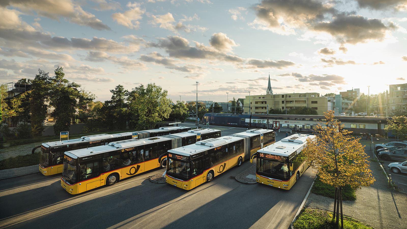 Verschiedene Postauto stehen im Morgenlicht am Bahnhof Bülach