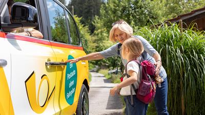 Two people board an electric London taxi from PostBus