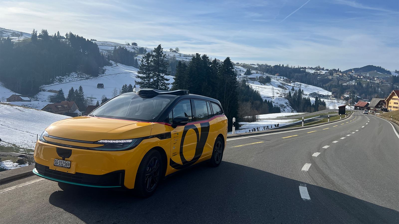 An automated electric car can be seen against a rural backdrop.
