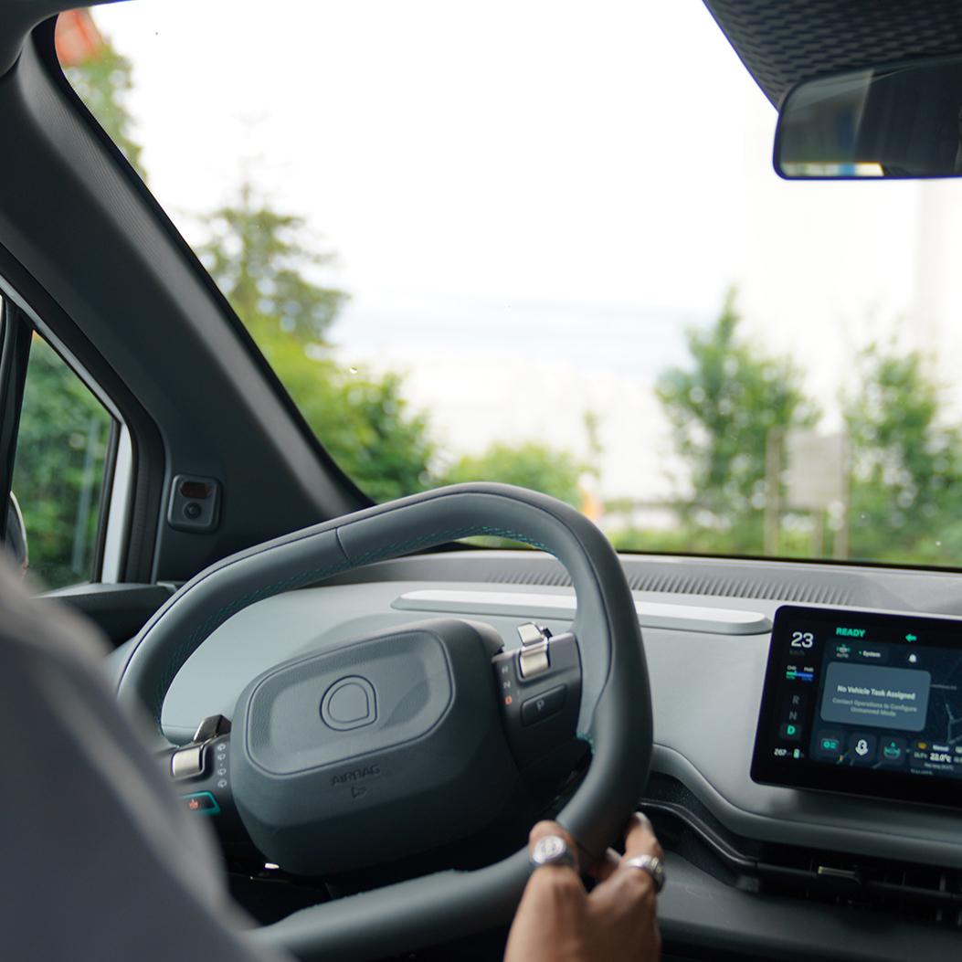 Una persona è al volante di un’auto moderna; sul display è visibile un sistema di navigazione