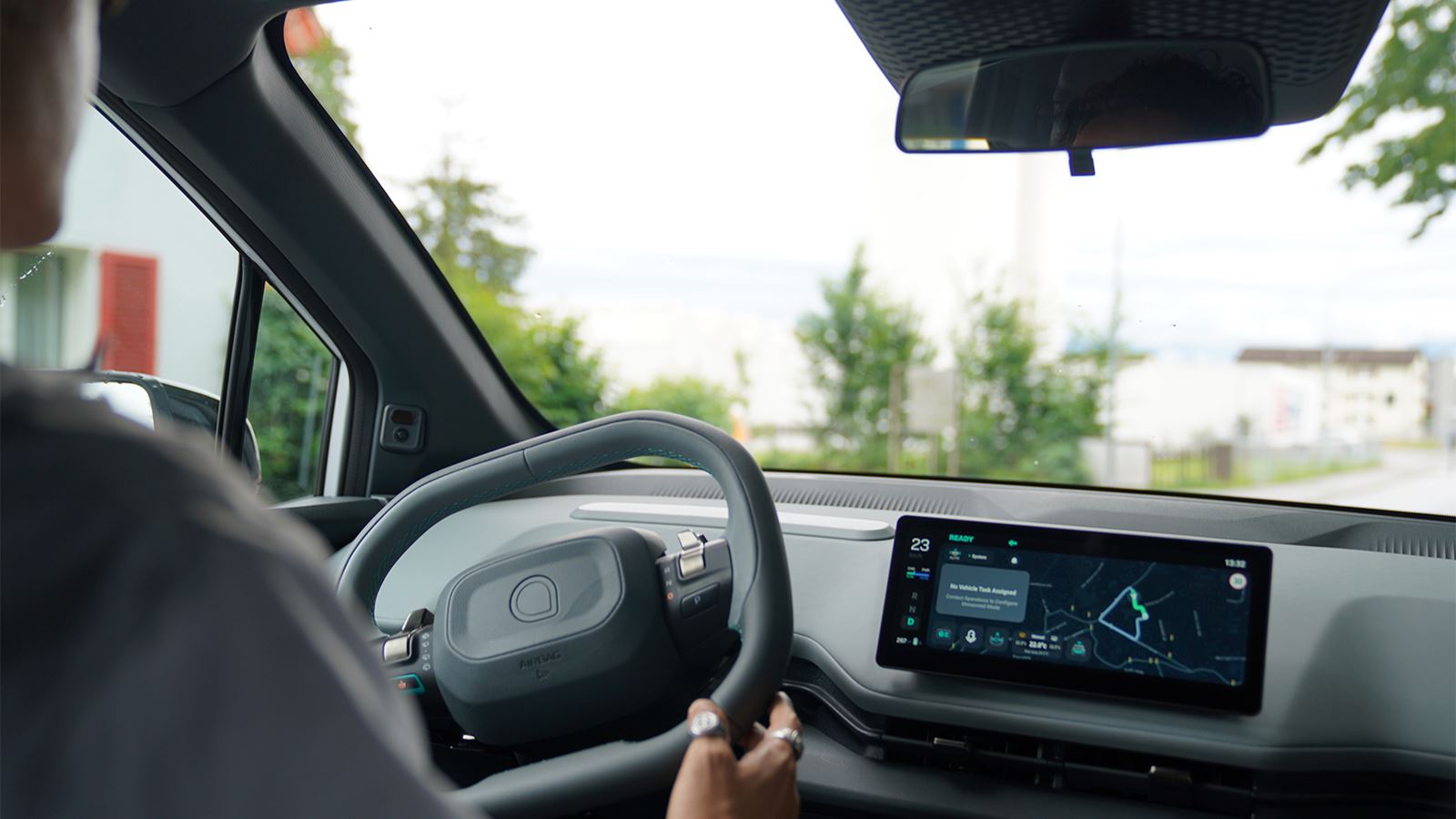 Person at the wheel of a modern car; a navigation system is visible on the display