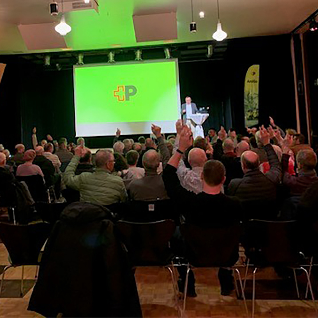 Public event in the community hall. AmiGo presentation in front of a canvas with the Swiss Post logo.