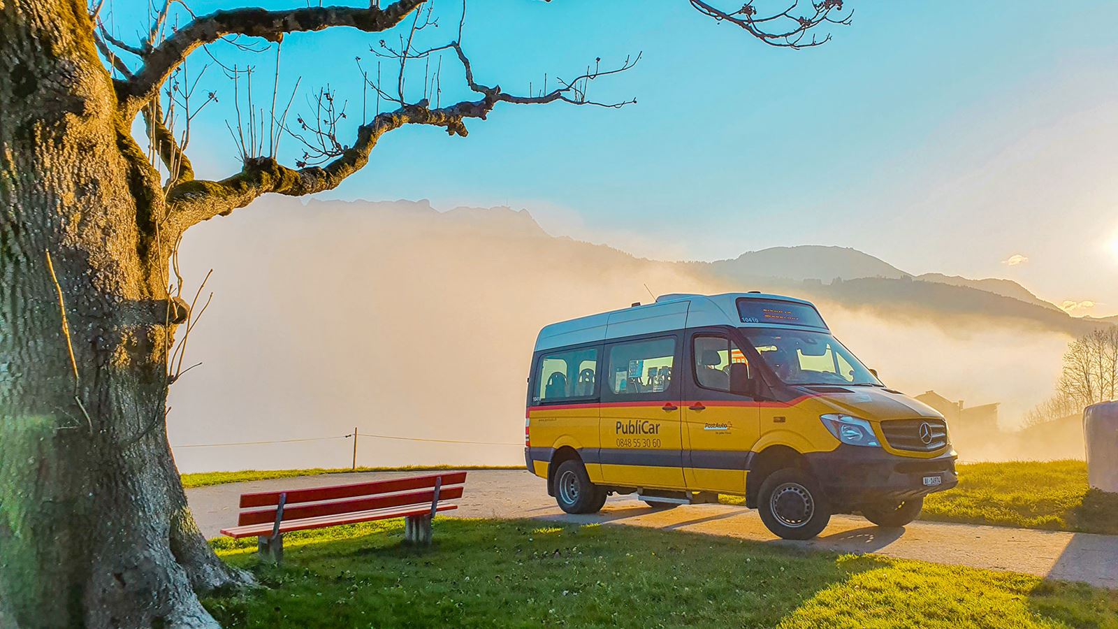 A Postbus minibus labelled with the word “PubliCar” on a hill. 