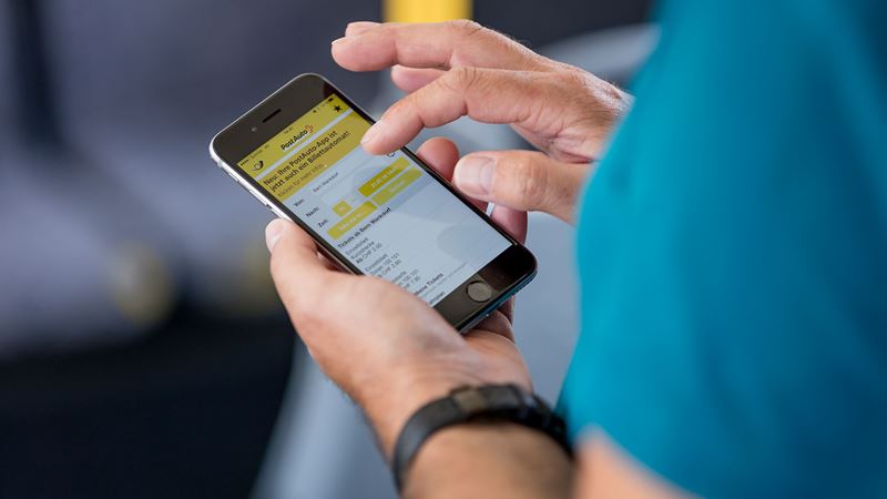 Gros plan sur les mains d’une personne en train d’utiliser l’application CarPostal. 