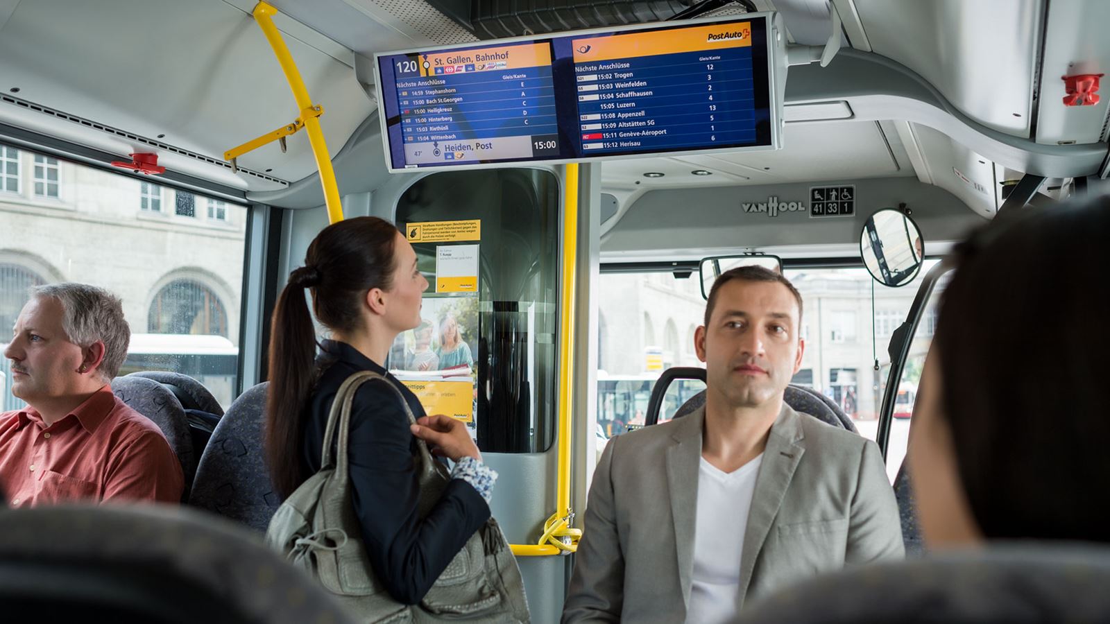 A passenger looks up information on a Postbus screen display.