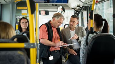 Deux collaborateurs dans un car postal discutent d’une procédure en regardant un document. 