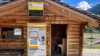 abris CarPostal en bois. À l’intérieur se trouve un piano brun avec une chaise