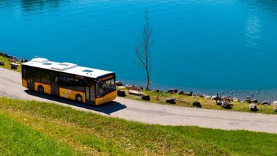 A Postbus driving along a lake