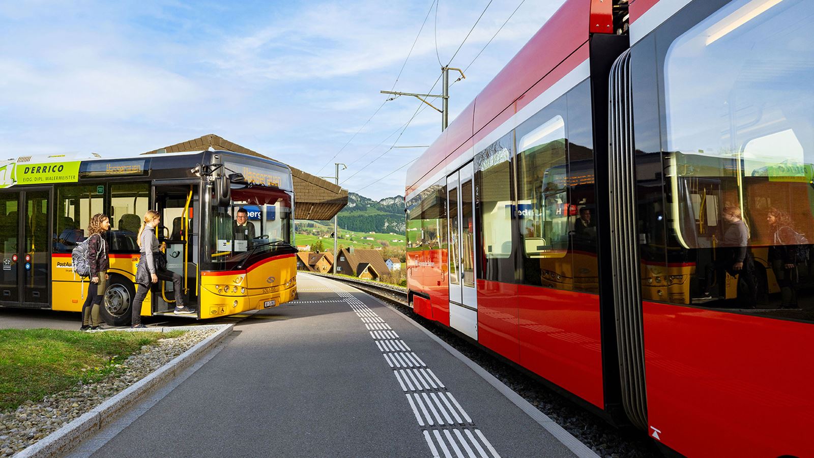 A Postbus waits at the Hirschberg stop for passengers arriving on Appenzell Railways.