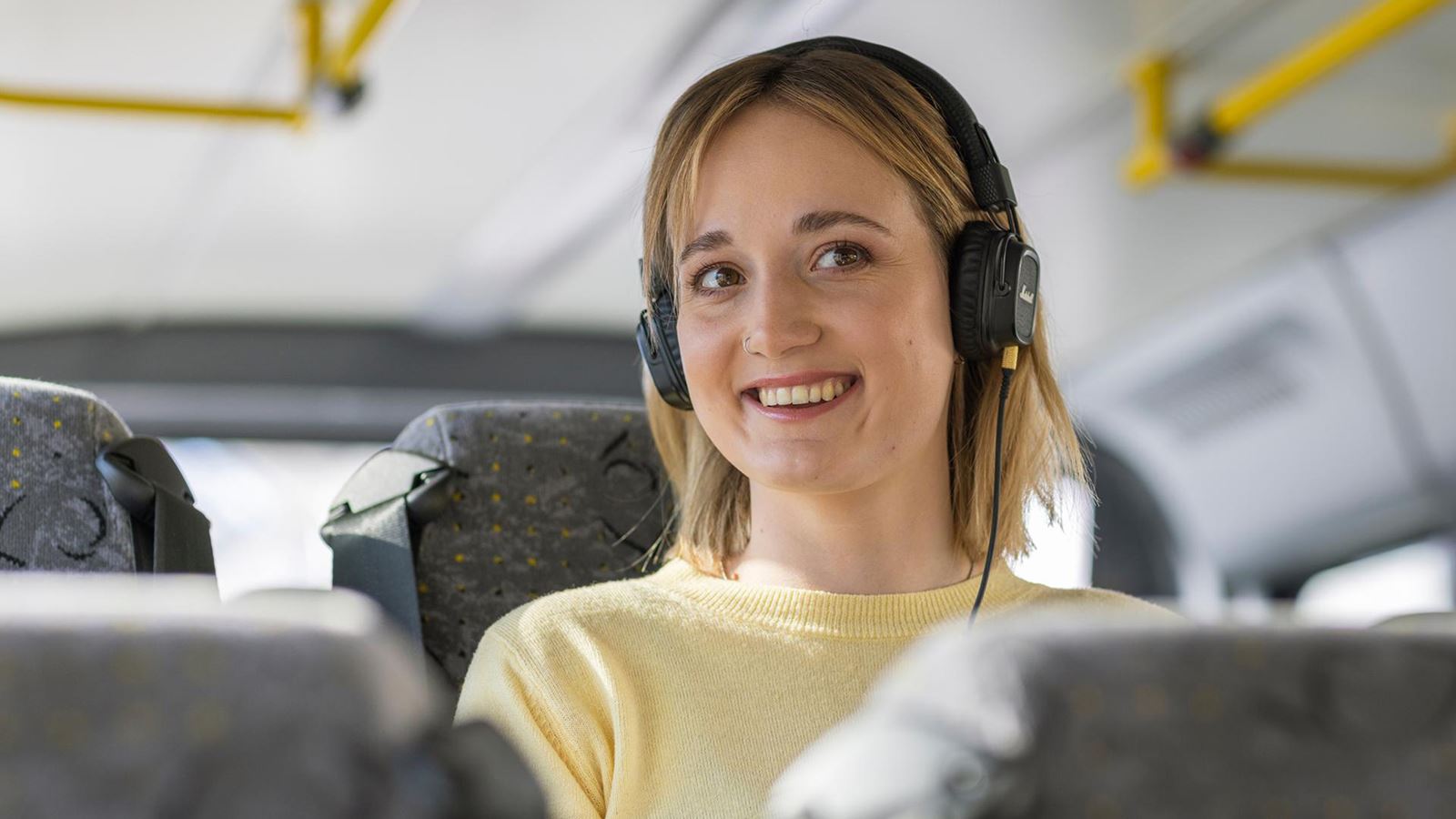 A young woman wearing headphones in a Postbus.